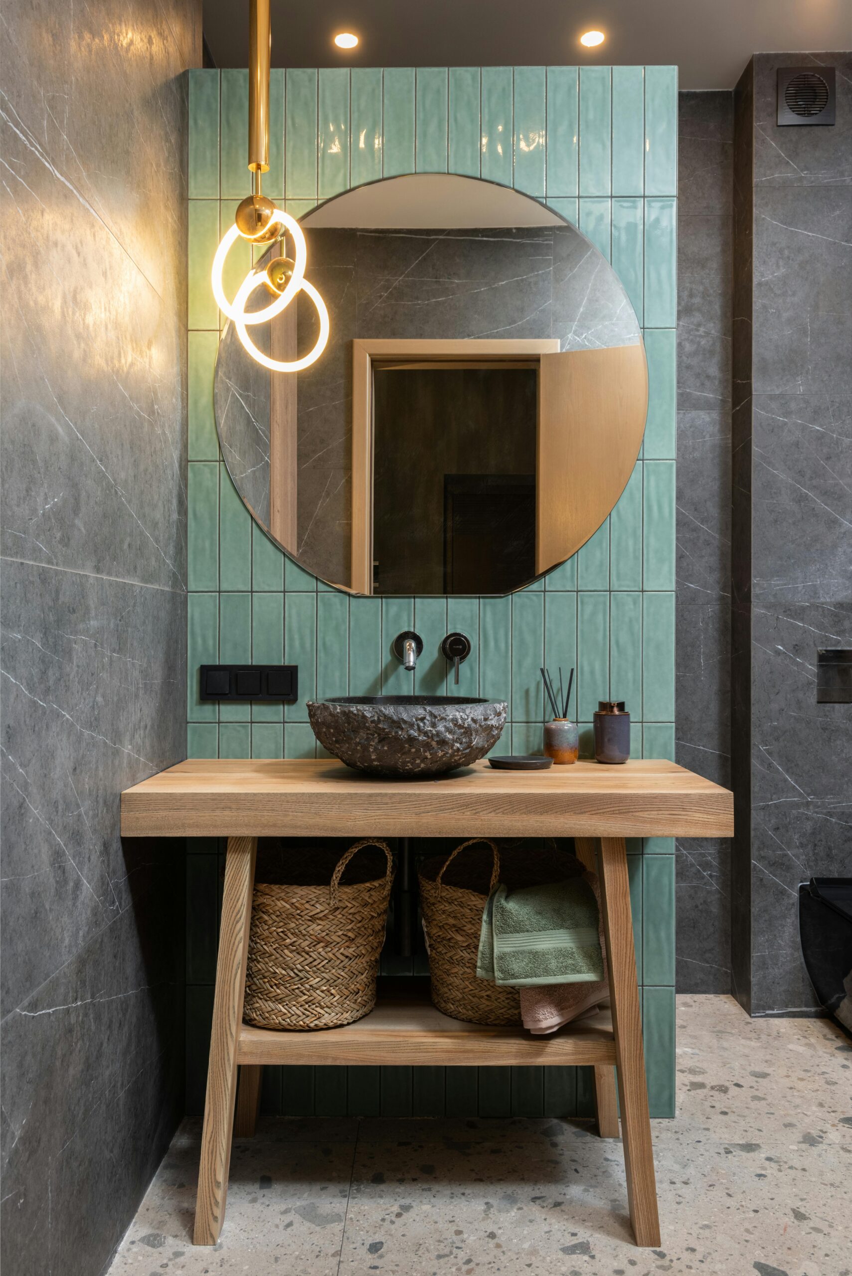 Stylish bathroom featuring a round mirror, washbasin, and elegant lighting.